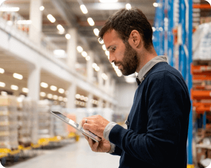 Man in warehouse, looking at tablet