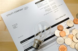 An energy bill, with cash and a bulb placed on top.