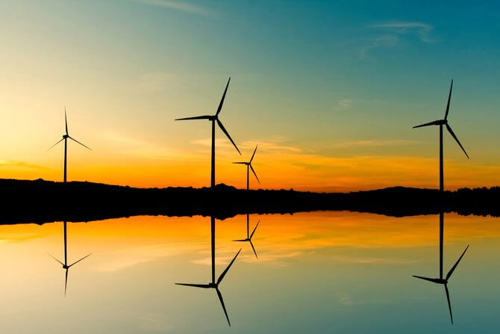wind farm reflected in water at sunset